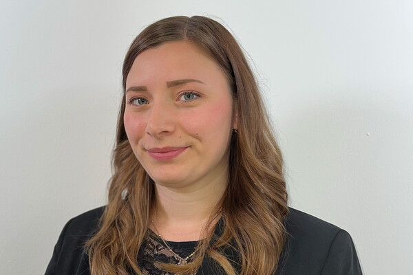 Porträt von Bea Schönberg mit langen, gewellten braunen Haaren, die freundlich in die Kamera lächelt.